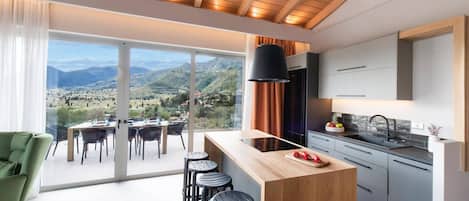 A modern kitchen with a large island, a dining area with a view, and a bar area with stools.