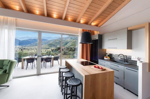 Una cocina moderna con una isla grande, un área de comedor con vistas y una barra con taburetes.