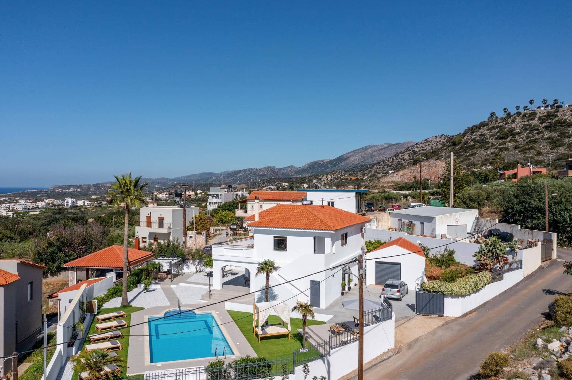 Zona residencial amb piscina, edificis blancs i vistes al mar i a les colines.