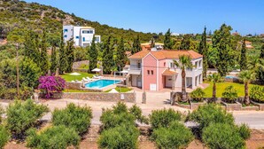 Ein zweistöckiges Haus mit Swimmingpool, umgeben von Grünflächen und weiteren Gebäuden.