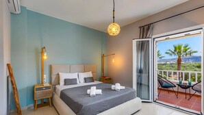 Ein Schlafzimmer mit Bett, Nachttischen, einer Lampe, einem Balkon mit Stühlen und Tisch.