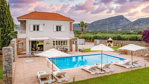 Ein zweistöckiges Haus mit Pool, Sitzgelegenheit im Freien und Blick auf Berge.