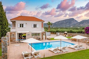 A two-story house with a swimming pool, outdoor seating, and a view of mountains. - Villa Argi by Villa Plus (Sissi)