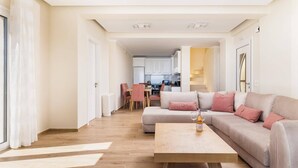 A modern living room with a sofa, coffee table, and a view into the kitchen.