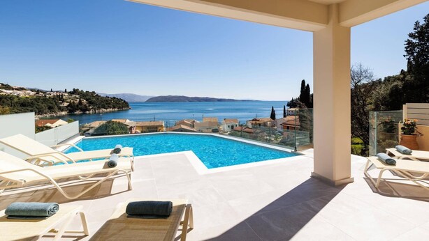 A poolside view with a clear blue sea and distant hills.