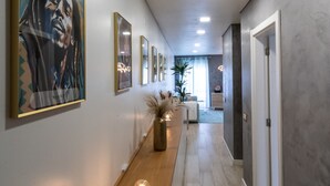 Ein Flur mit einer hölzernen Sitzbank, gerahmten Kunstwerken und einem Blumentopf.