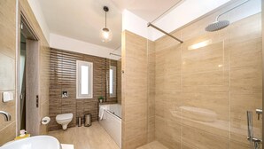 Une salle de bain moderne avec une baignoire sur pieds, une douche avec un pommeau de douche amovible et des toilettes.