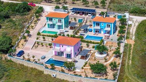 Un grand immeuble résidentiel à plusieurs étages, doté d’une piscine, de panneaux solaires et d’un espace de stationnement clôturé.