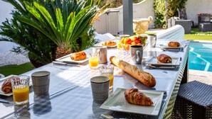 An outdoor breakfast setup with croissants, juice, and coffee on a table by a pool. - Villa Bohemienne by Villa Plus (Plaissan)