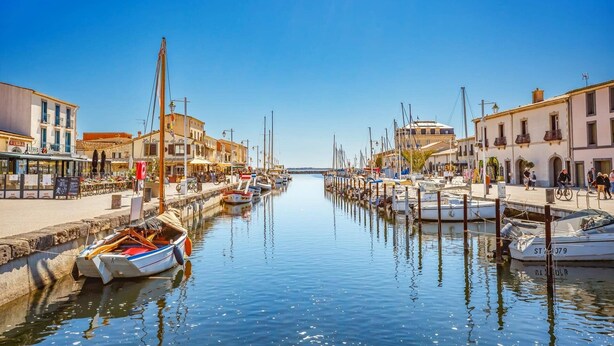 A marina with boats docked along a waterfront, surrounded by buildings with outdoor seating areas. - Villa Bohemienne by Villa Plus (Plaissan)