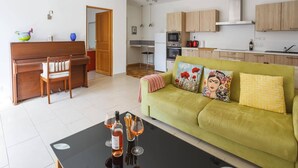 Una sala de estar moderna con un sofá verde, una mesa de centro de madera y un comedor con un piano.