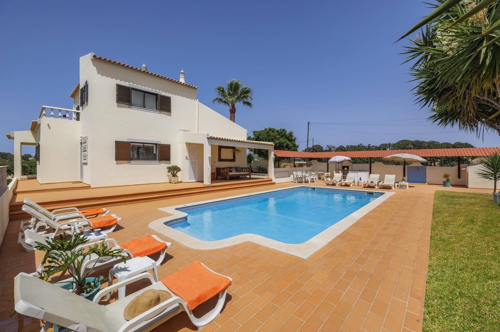 Une maison à deux étages dotée d’une piscine, d’un espace salon extérieur et d’un patio couvert.