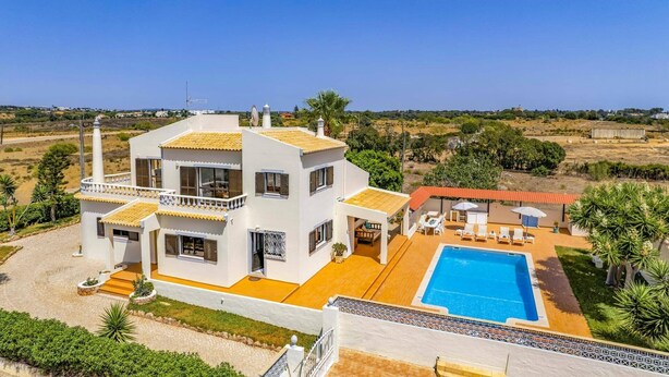 Une maison moderne à deux étages, dotée d’une piscine, entourée de verdure et offrant une vue dégagée sur le paysage.