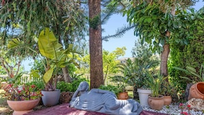 A garden with a statue, potted plants, and a paved area. - Villa Casa Jaska by Villa Plus (Urbanización Riviera Sol)