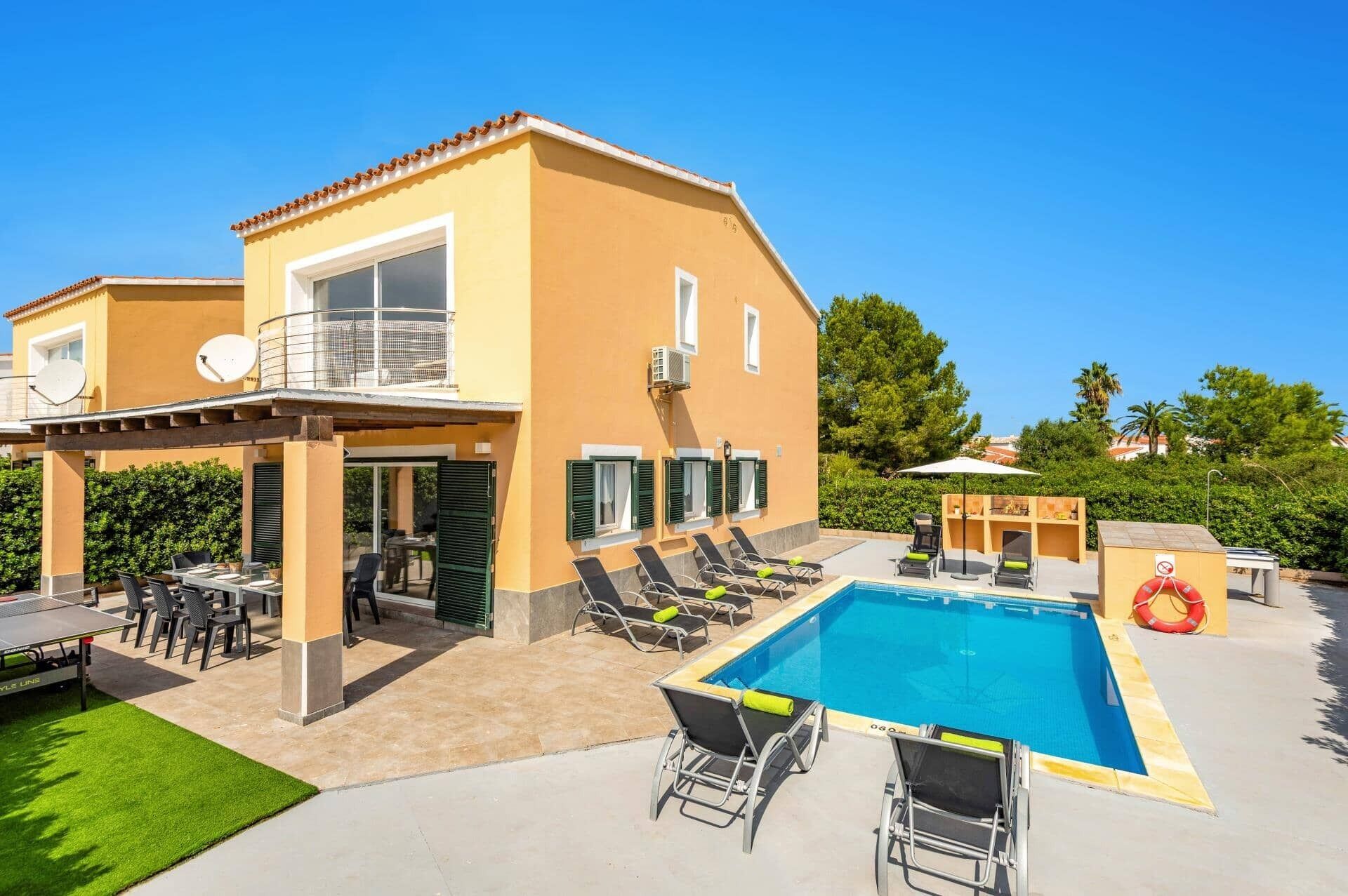 A two-story building with a swimming pool, outdoor seating, and a covered patio area.
