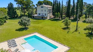 Une maison à deux étages avec une piscine et un espace extérieur aménagé pour se détendre.