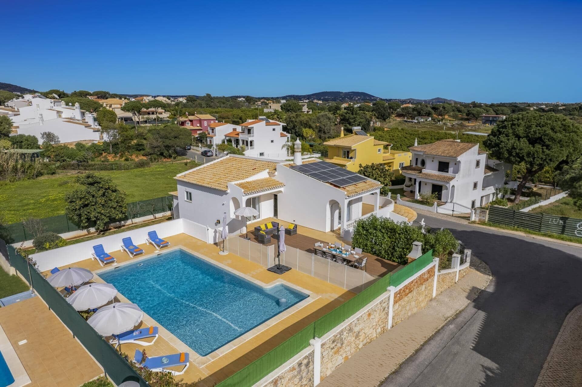 Ein Wohnhaus mit Swimmingpool, mehreren Liegestühlen und Blick auf die umliegende Nachbarschaft.