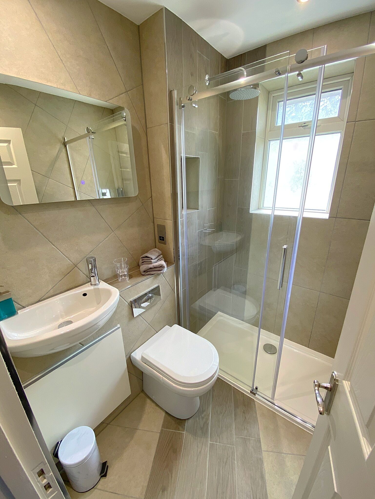 A modern bathroom with a glass-enclosed shower, a sink, and a toilet.