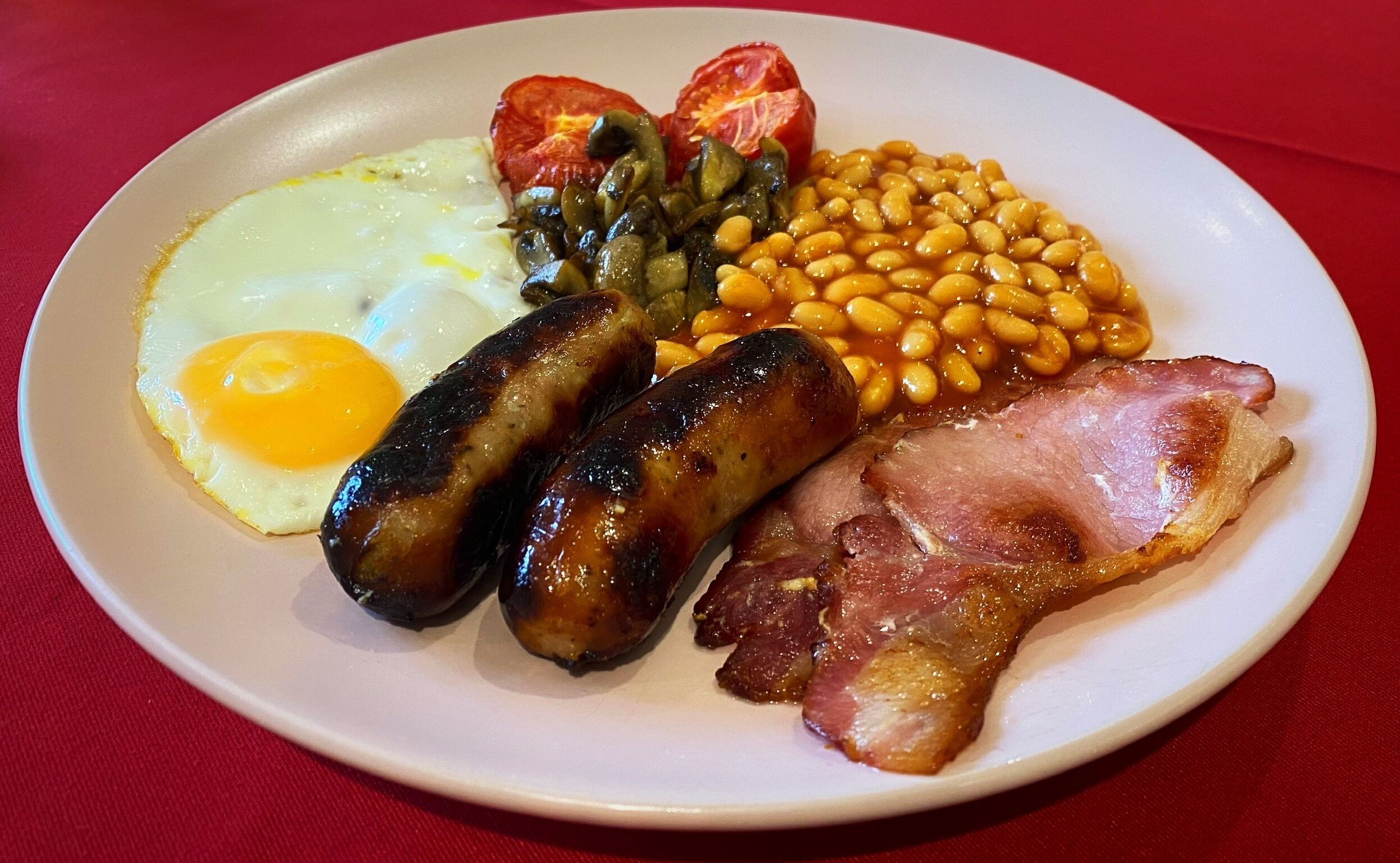 A plate with eggs, sausages, beans, tomatoes, and bacon.