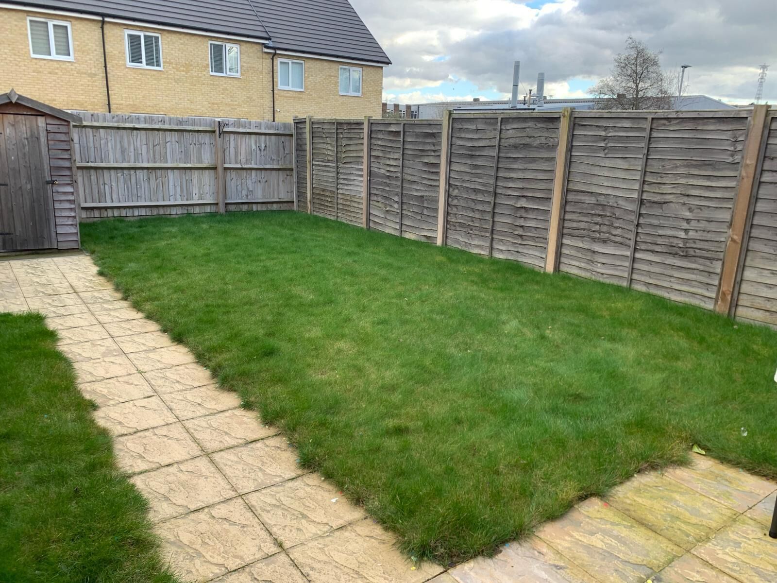 A backyard with a paved patio area and a wooden fence.