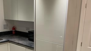 A kitchen with a large refrigerator, cabinets, a countertop, and a fire extinguisher. - Pristine 3-bed House in Grays (Grays)