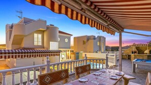 Une terrasse sur le toit avec une table à manger pour quatre personnes, une piscine et une vue sur les bâtiments voisins.