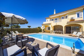 Un espace aménagé au bord de la piscine, avec des chaises longues, une table et un parasol.