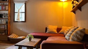 Een gezellige woonkamer met een houten plafond, een zithoek, een bijzettafeltje en een boekenkast.