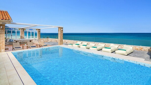 A pool area with lounge chairs and a view of the ocean. - Villa Ionio Beach House by Villa Plus (Ano Vasilikos)