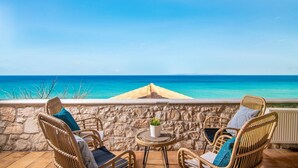 A balcony with wicker chairs, a small round table with a potted plant, and a view of the sea. - Villa Ionio Beach House by Villa Plus (Ano Vasilikos)
