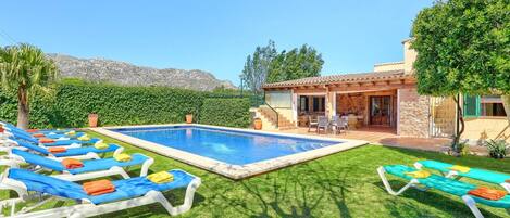 A pool area with lounge chairs and a patio.