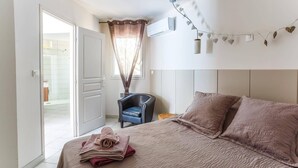 Une chambre à coucher comprenant un lit, une chaise et une porte donnant sur une salle de bain.