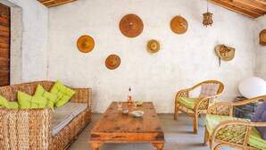 Une pièce chaleureuse avec un canapé en osier, une table basse en bois et des chaises en osier.