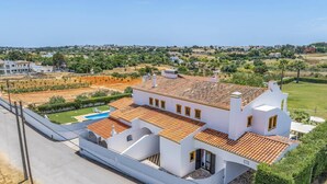 A white villa with a tiled roof, a swimming pool, and a view of a coastal landscape. - Villa Luis Gale by Villa Plus (Vale Rebelho)