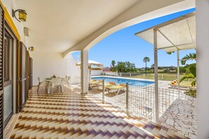 A covered outdoor area with a pool, chairs, and a tiled floor. - Villa Luis Gale by Villa Plus (Vale Rebelho)