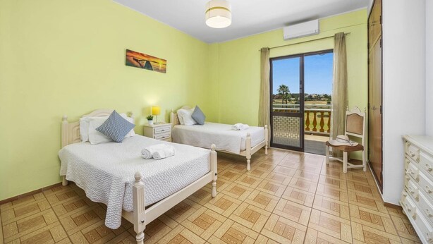 A hotel room with two beds, a balcony with a view, and a painting on the wall. - Villa Luis Gale by Villa Plus (Vale Rebelho)