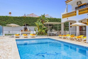 A swimming pool with lounge chairs and a barbecue area.