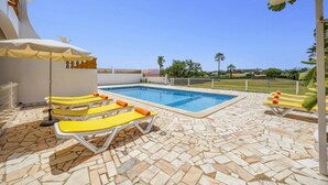A swimming pool with lounge chairs and a tiled deck. - Villa Luis Gale by Villa Plus (Vale Rebelho)