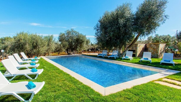 A rectangular swimming pool with white lounge chairs and blue towels arranged around it. - Villa Maria Rosaria by Villa Plus (Ceglie Messapica)