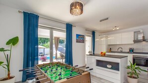 A modern kitchen with white cabinets, a foosball table, and a view of the outside. - Villa Melani Vita by Villa Plus (Marčana)