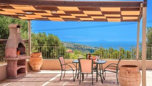Eine Terrasse im Freien mit Backsteinfußboden, einem Steinofen und einem Tisch mit Stühlen.