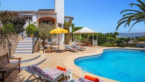 A pool area with lounge chairs, a pergola, and a view of the sea. - Villa Murales by Villa Plus (El Tosalet)