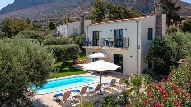 A two-story building with a swimming pool, outdoor seating, and a mountainous backdrop. - Villa Nefeli Green by Villa Plus (Chersonisos)