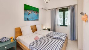 A bedroom with two beds, a painting of flamingos, a chandelier, and a window with curtains. - Villa Nefeli Green by Villa Plus (Chersonisos)