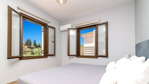A bedroom with a bed, a window, and an air conditioning unit. - Villa Observer by Villa Plus (Ionian Islands)