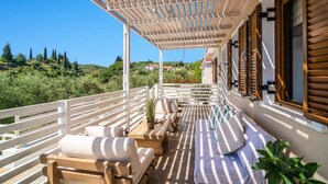 A covered outdoor seating area with wooden furniture and a view of the countryside. - Villa Observer by Villa Plus (Ionian Islands)