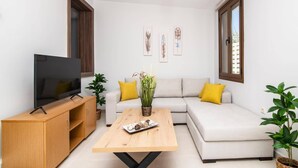 A modern living room with a sofa, a coffee table, a TV, and decorative plants. - Villa Observer by Villa Plus (Ionian Islands)