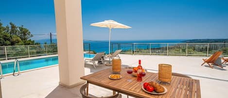 A wooden table with chairs and a view of the sea.