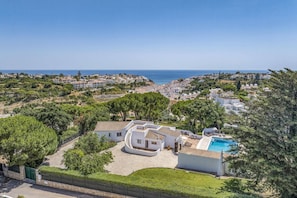 A residential area with a pool, surrounded by greenery and overlooking a coastal landscape. - Villa Pinehill by Villa Plus (Praia do Carvoeiro)