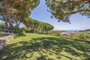 A well-maintained grassy area with stone walls and trees, overlooking a coastal town. - Villa Pinehill by Villa Plus (Praia do Carvoeiro)